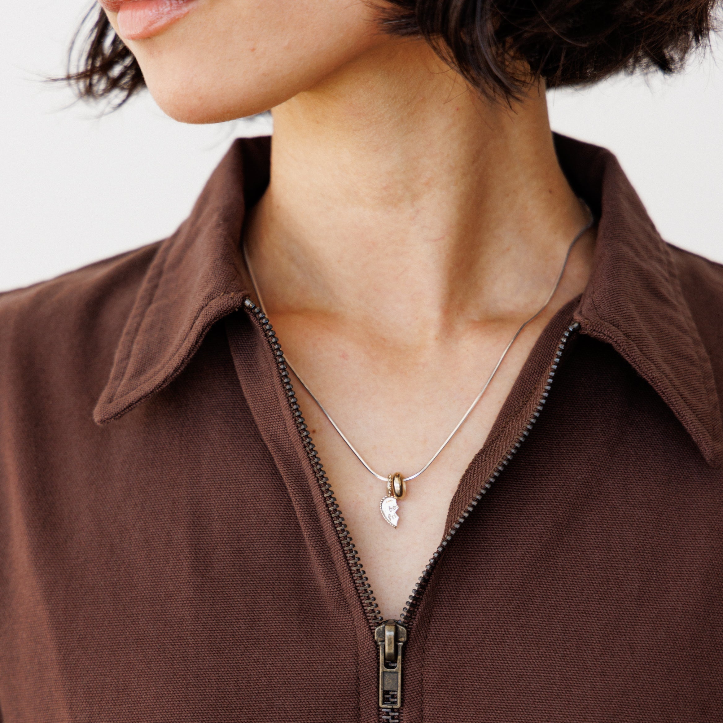 Close-up of a person wearing a brown dress with a necklace featuring a pendant.