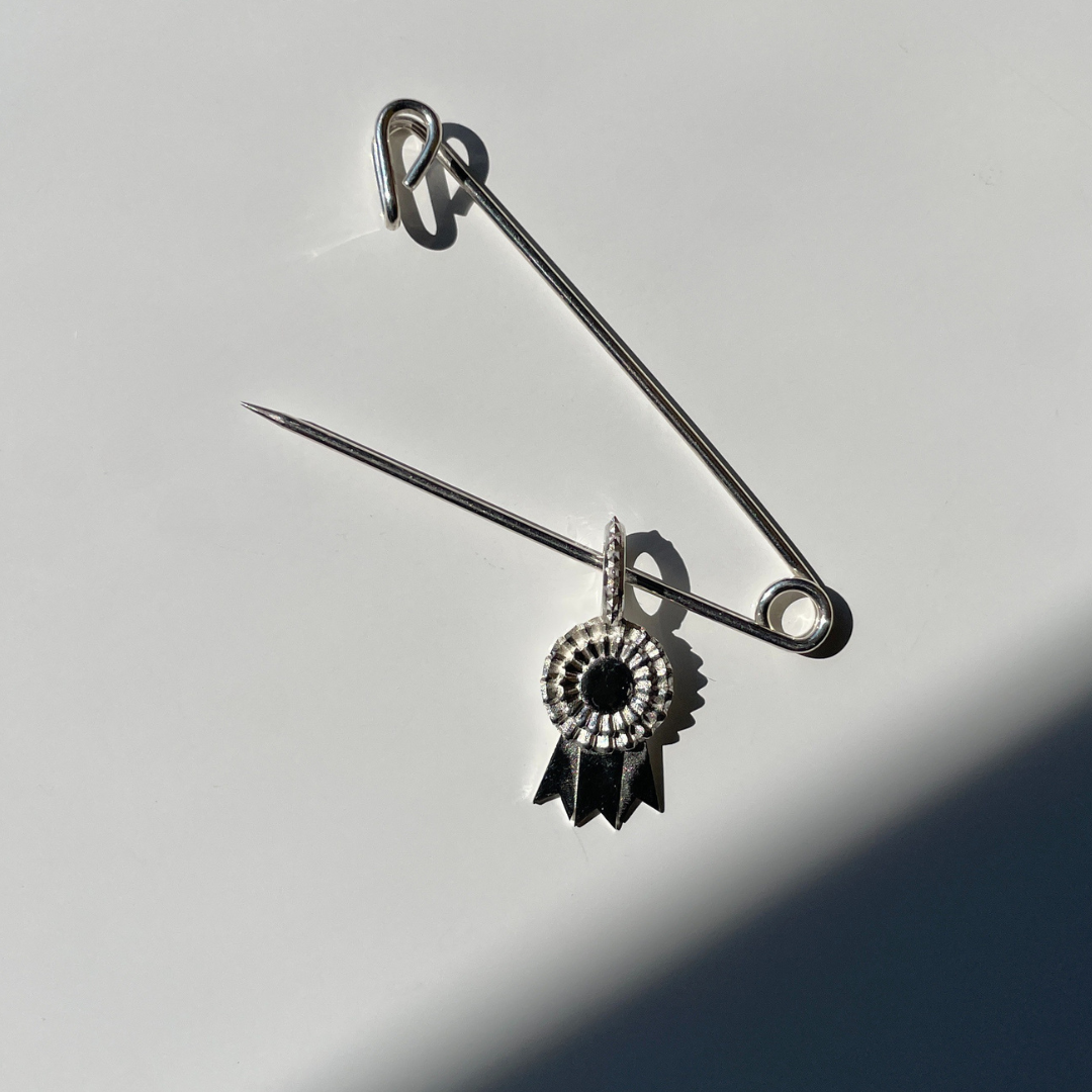 Silver safety pin with a decorative charm