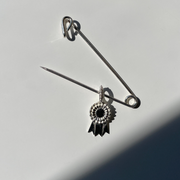 Silver safety pin with a decorative charm