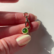 Hand holding a small green bead charm on a white background