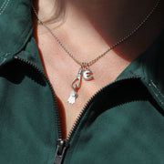 Close-up of a person wearing a green dress with a necklace featuring a 'E' and award pendant.