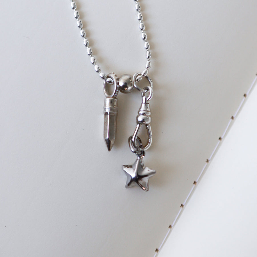 Silver necklace with key and star pendant on a white surface