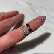 Close-up of a hand with multiple rings on a textured white surface