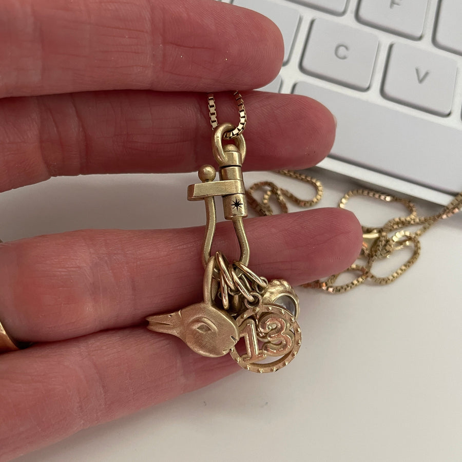 Gold key-shaped pendant with heart charm held between fingers against a keyboard background
