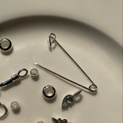 Collection of various silver charms and jewelry components on a beige plate.
