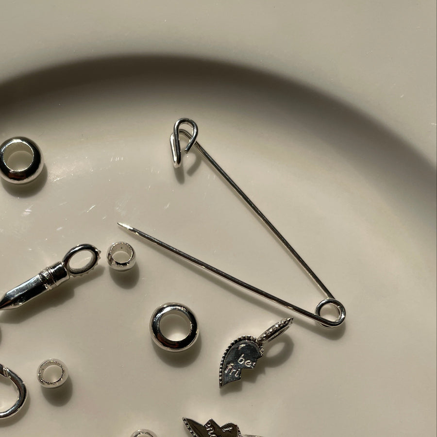 Collection of various silver charms and jewelry components on a beige plate.