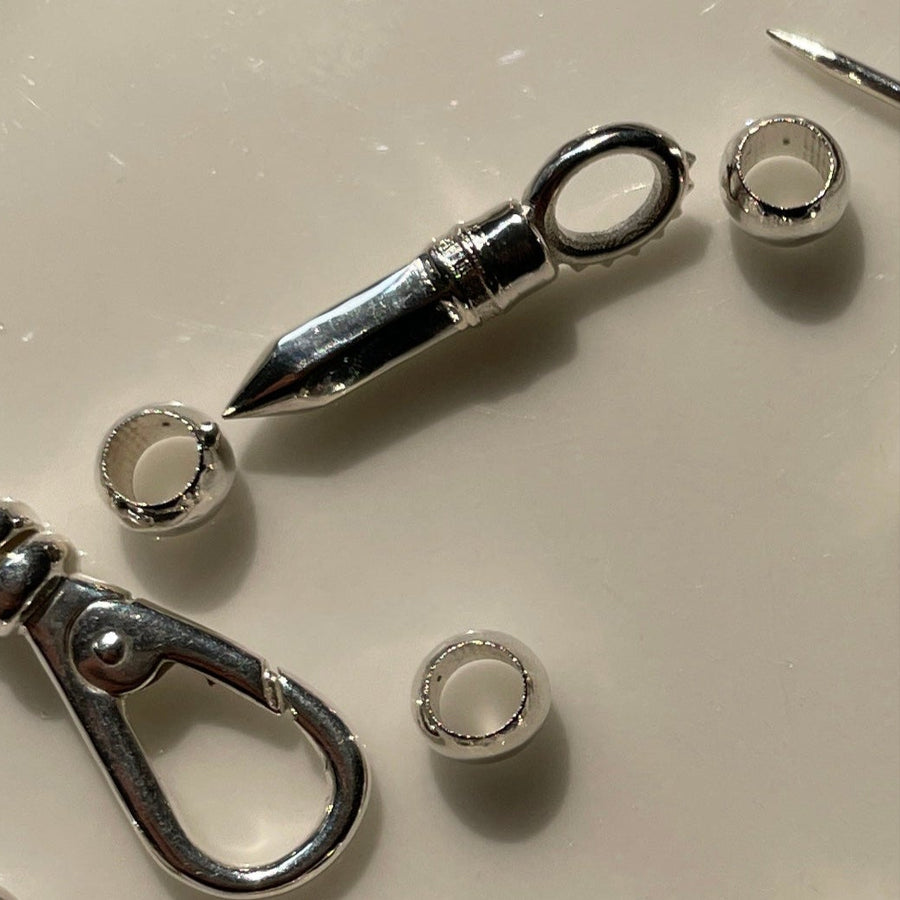 Collection of various silver charms and jewelry components on a beige plate.