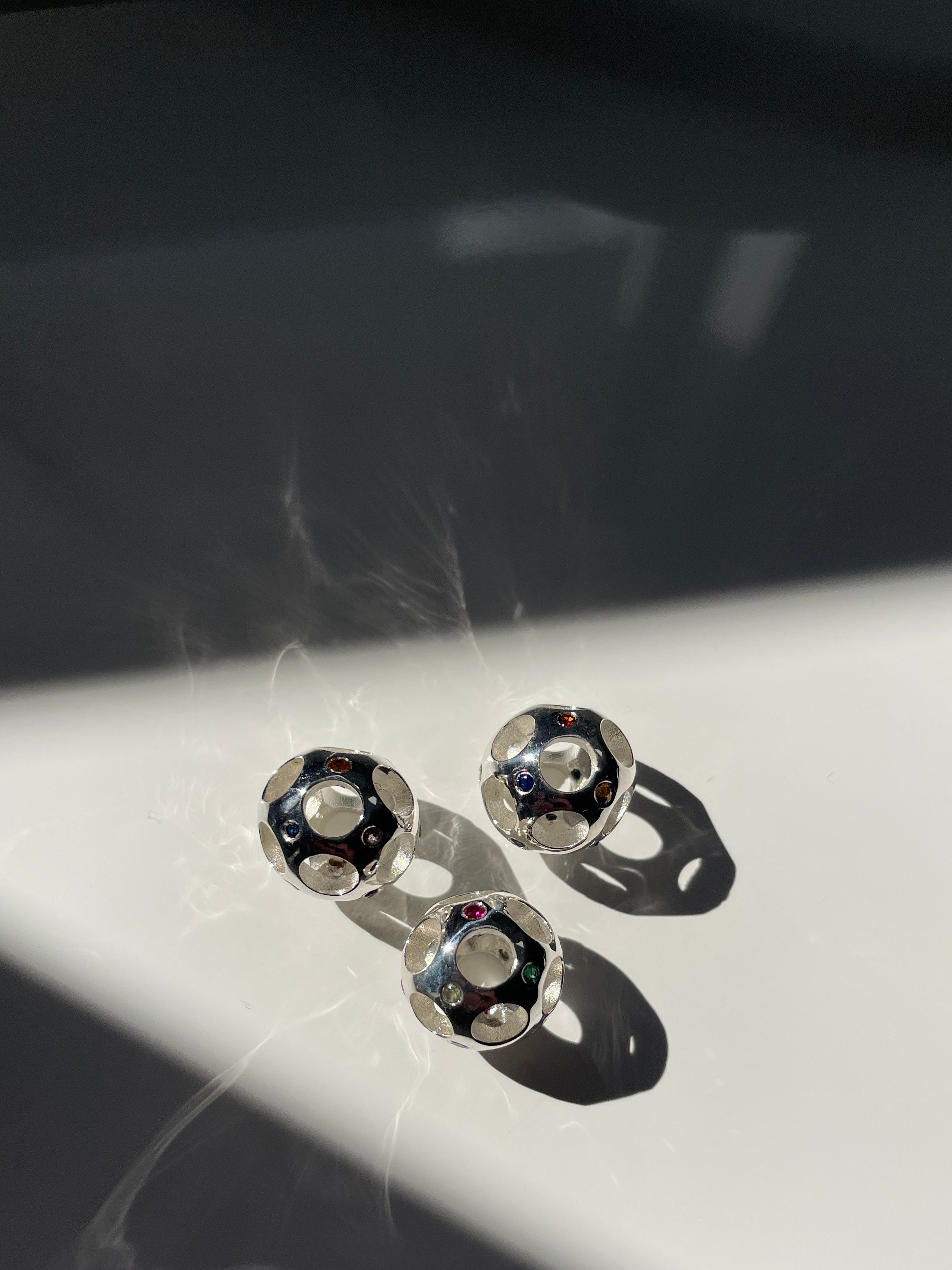 Silver gemballs with gemstones on a reflective surface