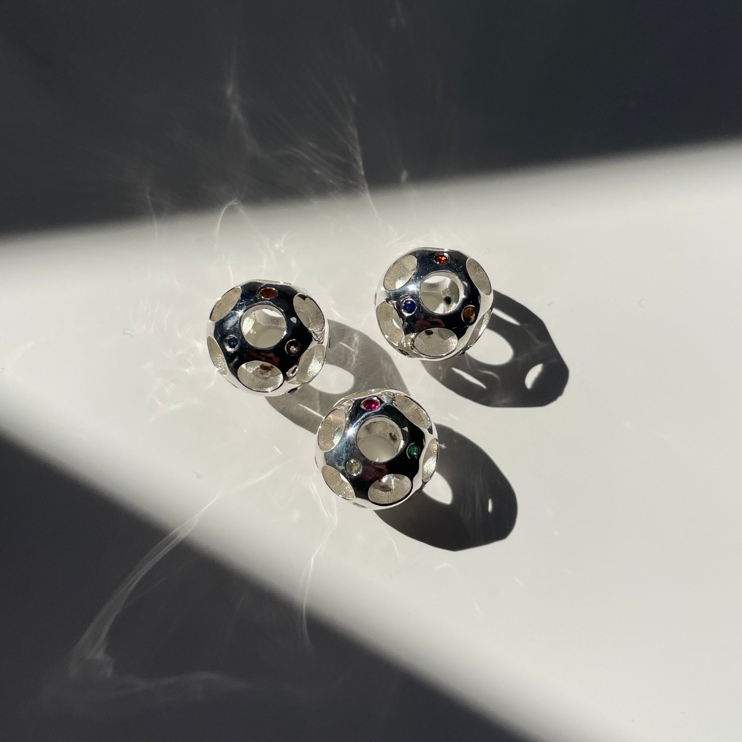 Silver beads with gemstones on a reflective surface