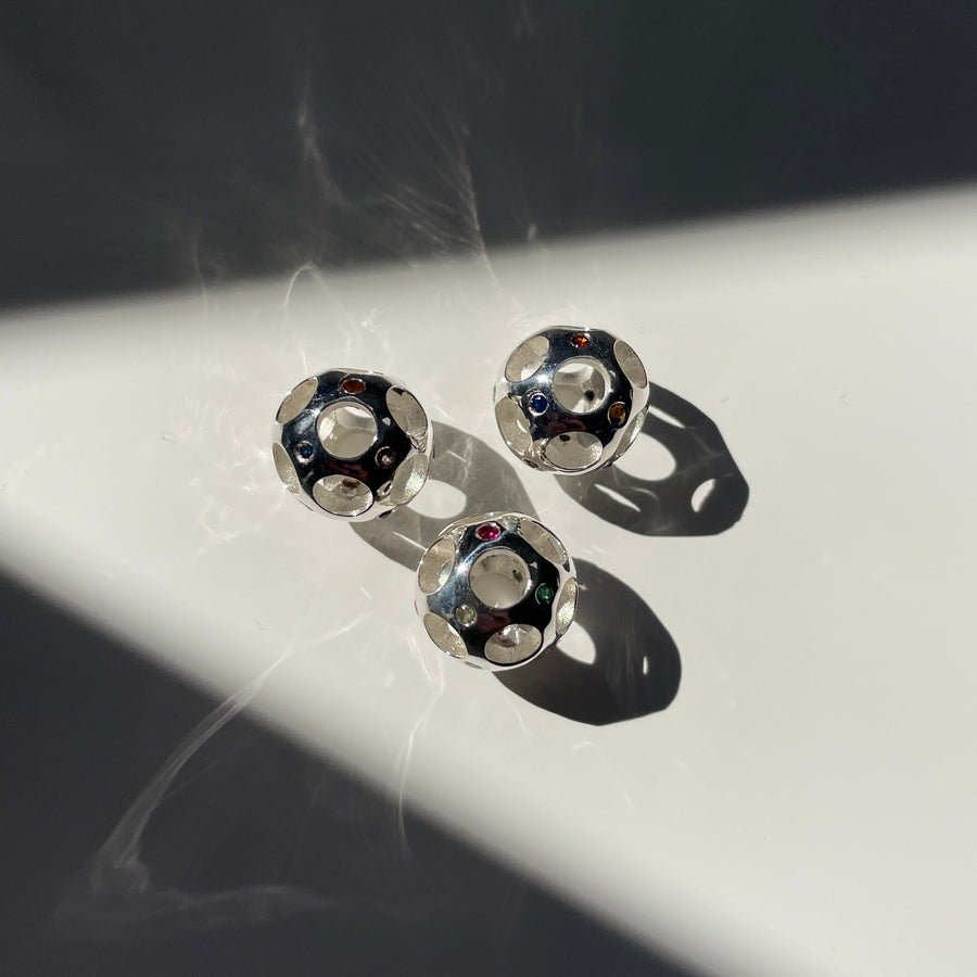 Silver beads with gemstones on a reflective surface