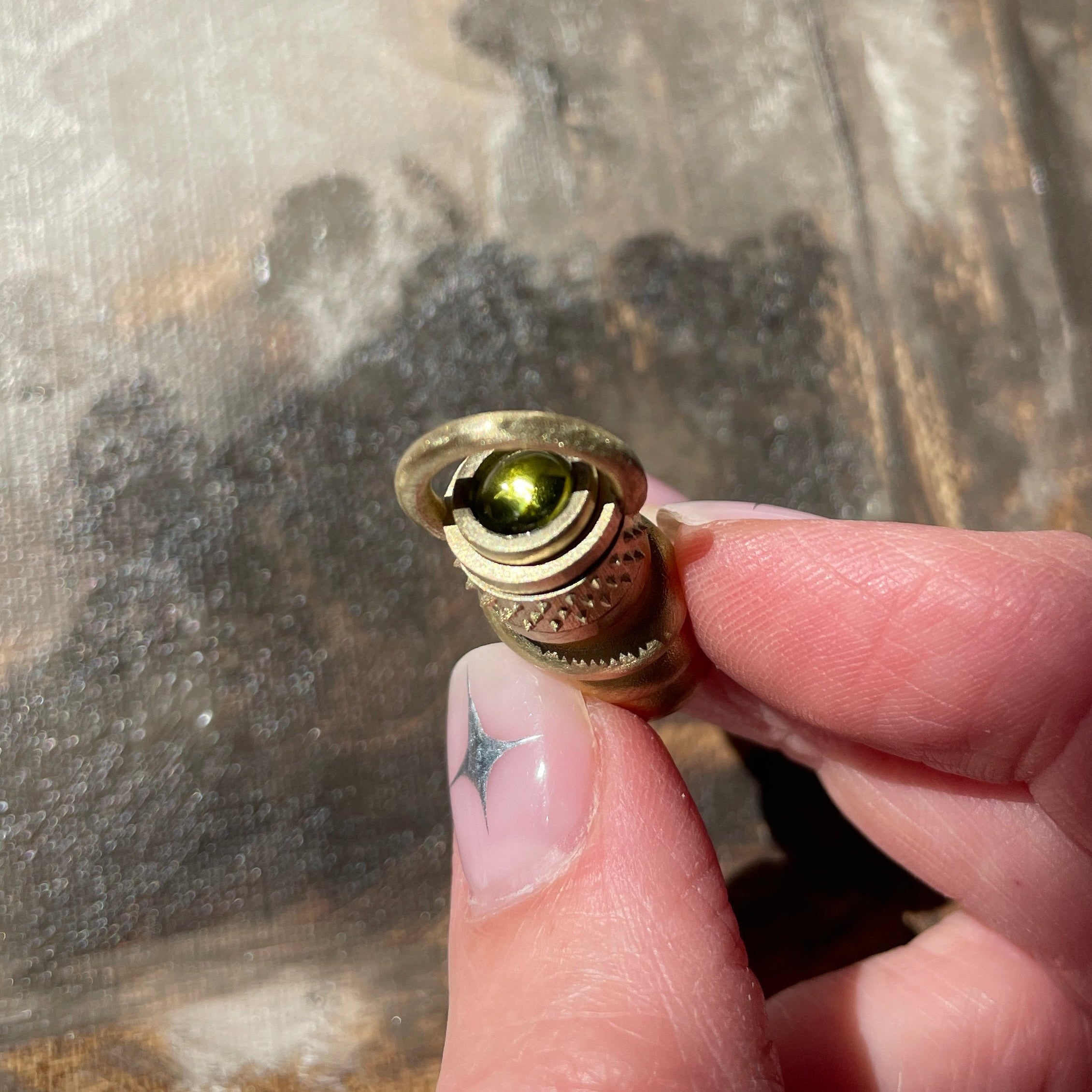 A solid gold perfume bottle with a peridot set on top.