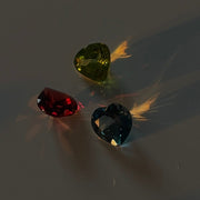 Three gemstones (red, green, and blue) on a gray background