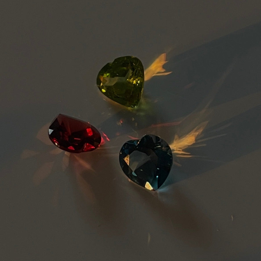 Three gemstones (red, green, and blue) on a gray background