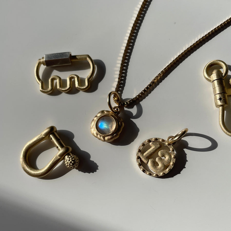 Gold jewelry pieces including a necklace and various pendants on a white background